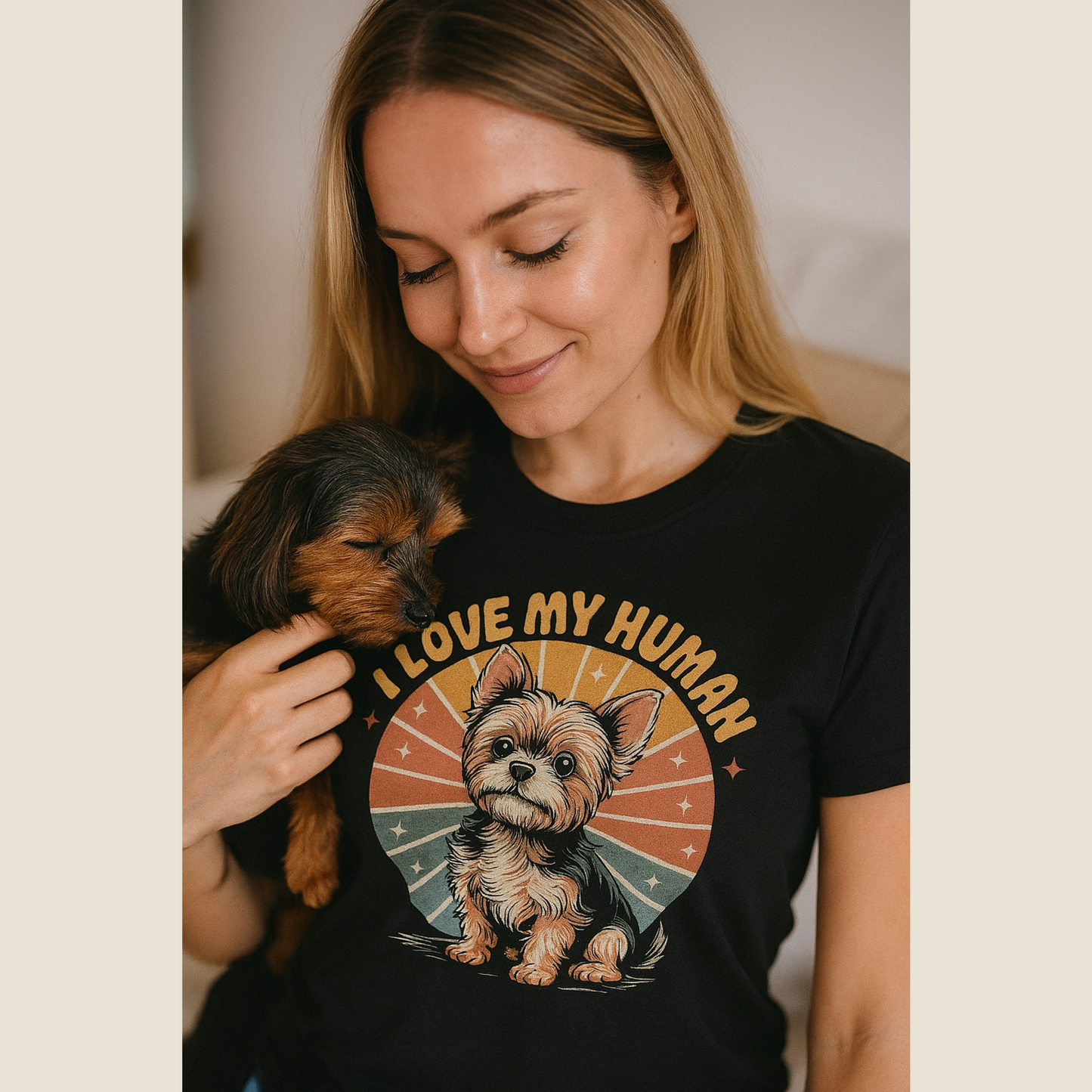 Woman wearing a black t-shirt with a dog graphic and 'I love my human' text, holding a small dog.