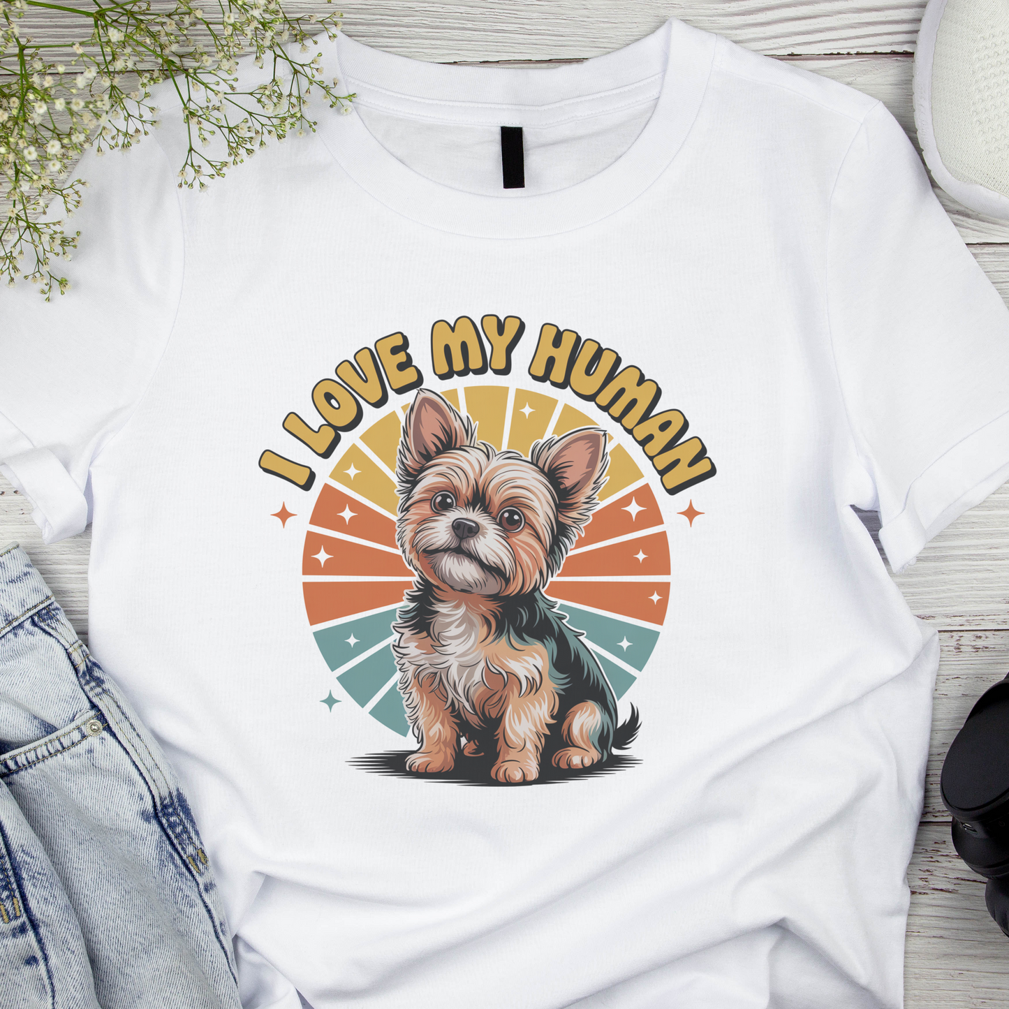 White t-shirt with a dog graphic and 'I Love My Human' text on a wooden surface.