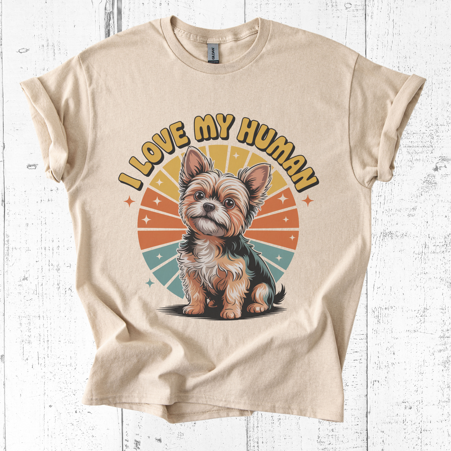 Beige t-shirt with a dog graphic and 'I Love My Human' text on a white wooden background