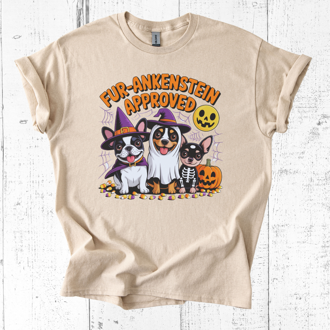 Beige t-shirt with Halloween-themed graphic of dogs in costumes on a white wooden background