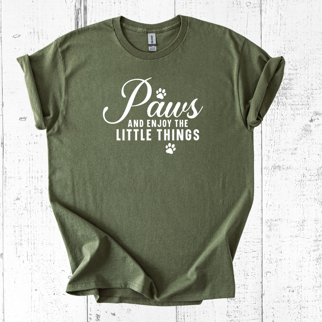 Green t-shirt with 'Paws and enjoy the little things' text on a white wooden surface