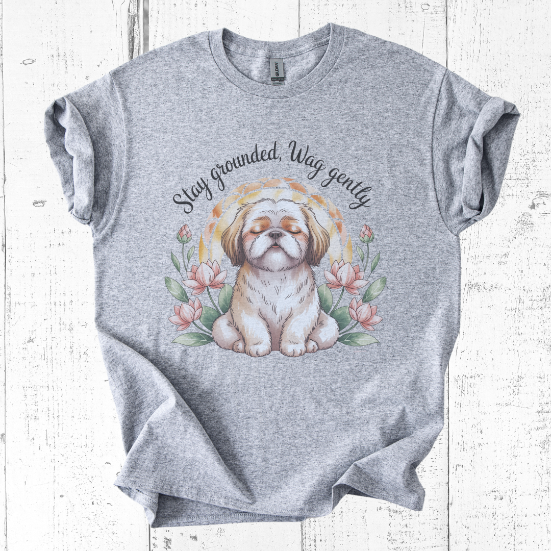 Gray t-shirt with a dog graphic and text 'Stay grounded, Wag gently' on a wooden surface.