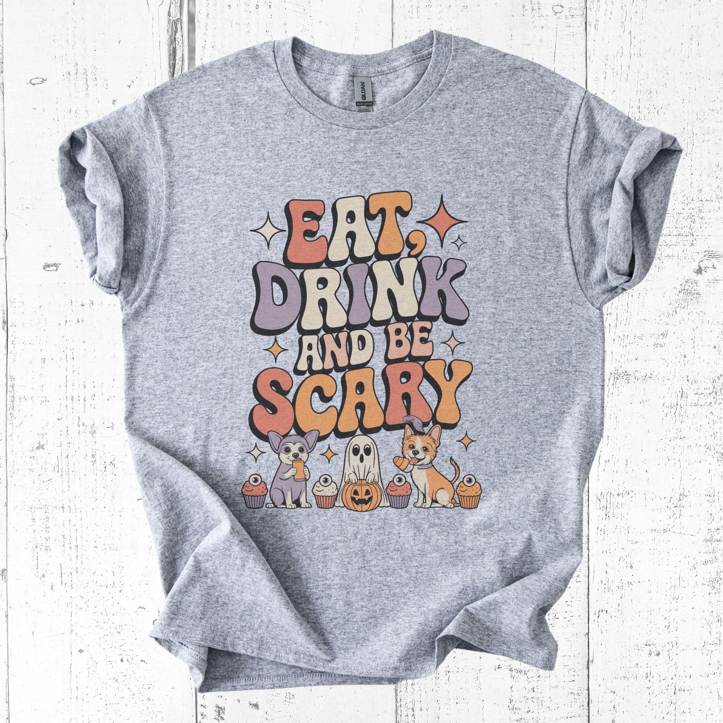 Gray t-shirt with Halloween-themed text and graphics on a white wooden background