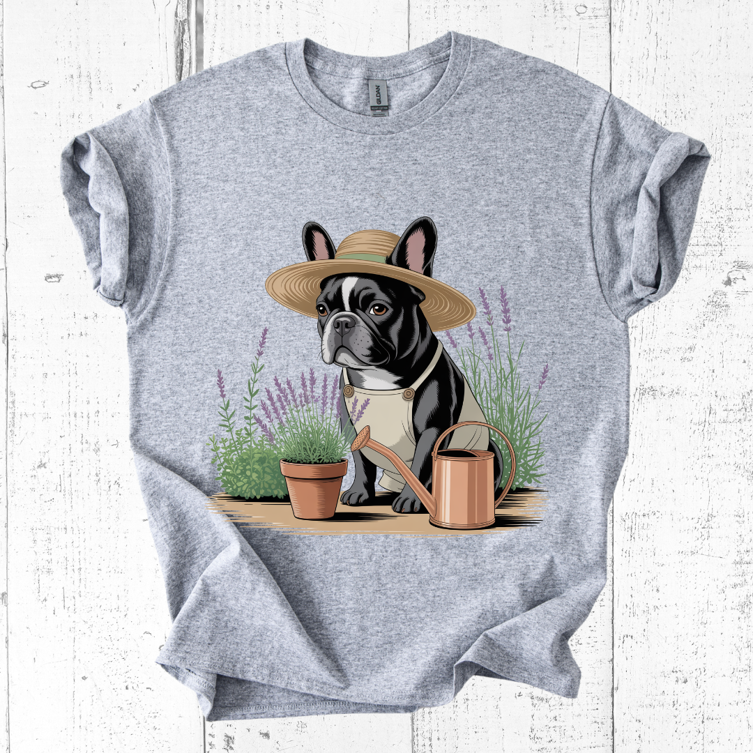 Gray t-shirt with a dog wearing a hat and holding a watering can graphic on a white wooden background