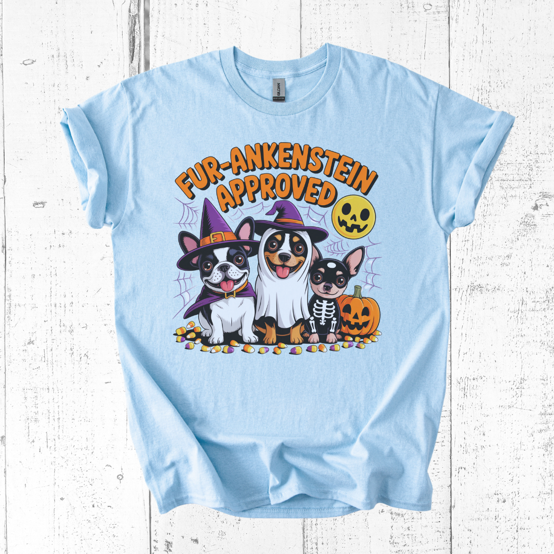 Light blue t-shirt with Halloween-themed design featuring dogs and text on a wooden surface.