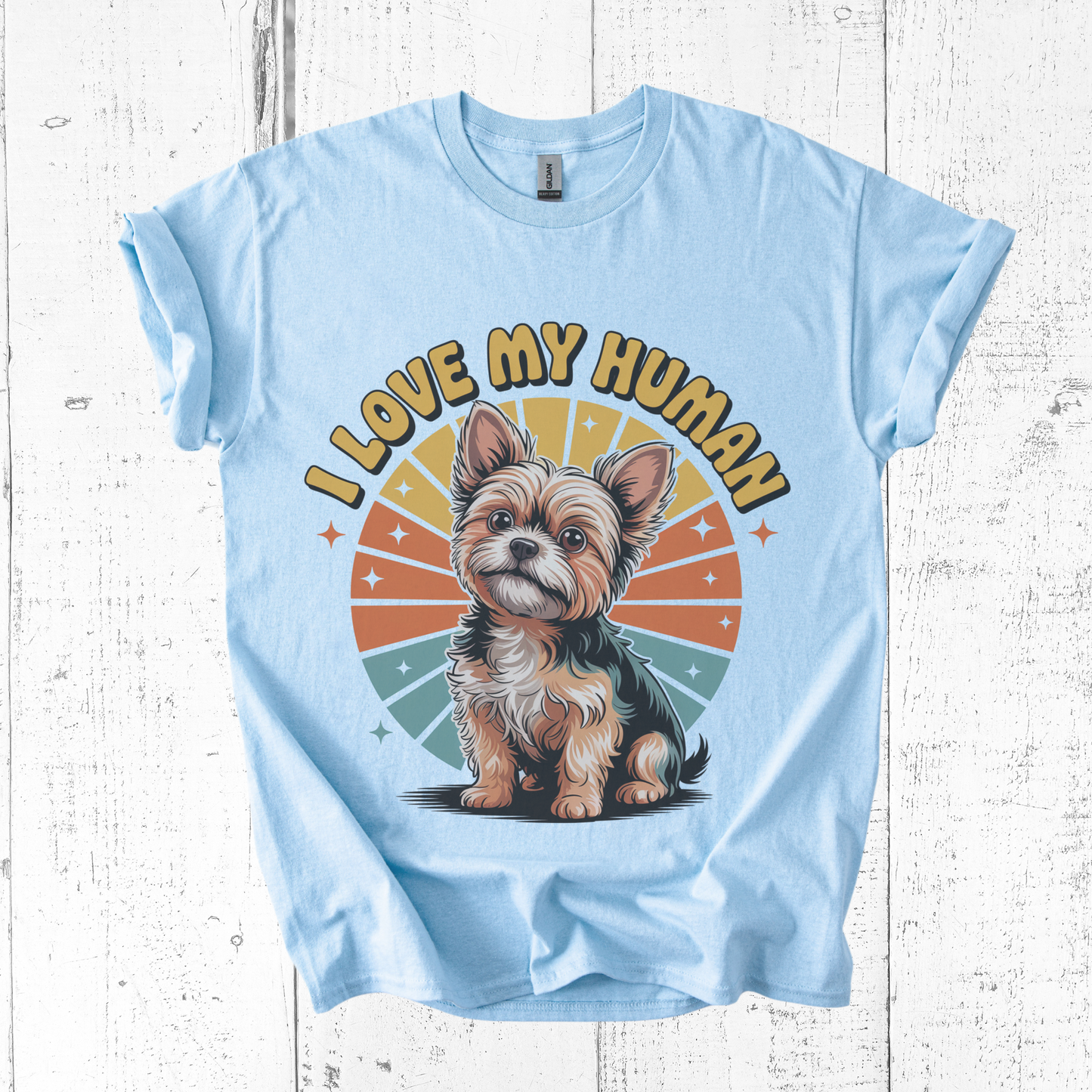 Light blue t-shirt with a dog graphic and 'I Love My Human' text on a wooden surface