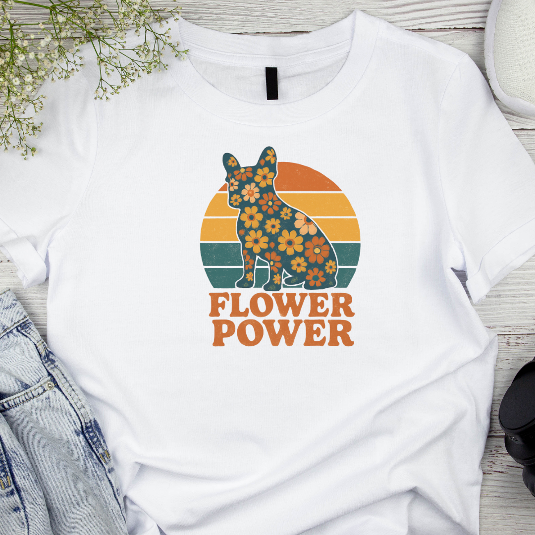White t-shirt with a colorful dog graphic and 'Flower Power' text on a wooden surface.