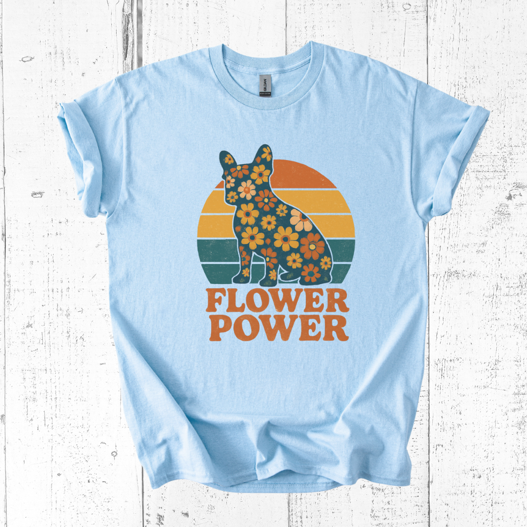 Light blue t-shirt with a graphic of a dog surrounded by flowers and 'FLOWER POWER' text on a white wooden background.