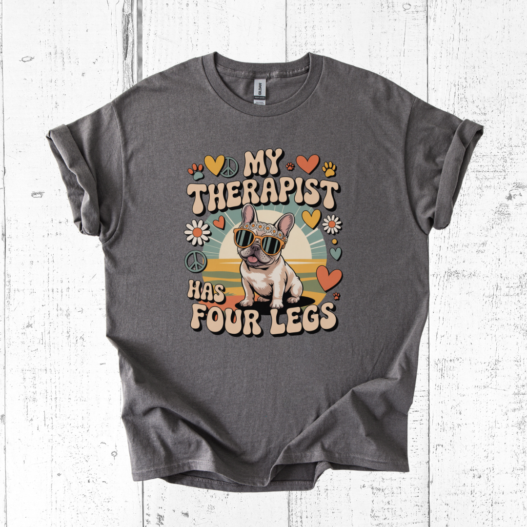 Gray t-shirt with a graphic of a dog and text 'My therapist has four legs' on a wooden surface.