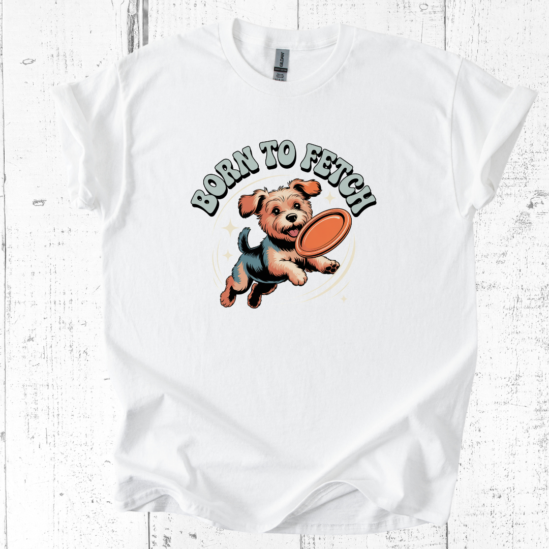 White t-shirt with a graphic of a dog holding a frisbee and 'Born to Fetch' text on a wooden surface.