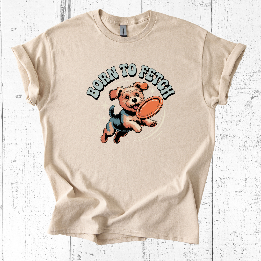 Beige t-shirt with a graphic of a dog and 'Born to Fetch' text on a white wooden background