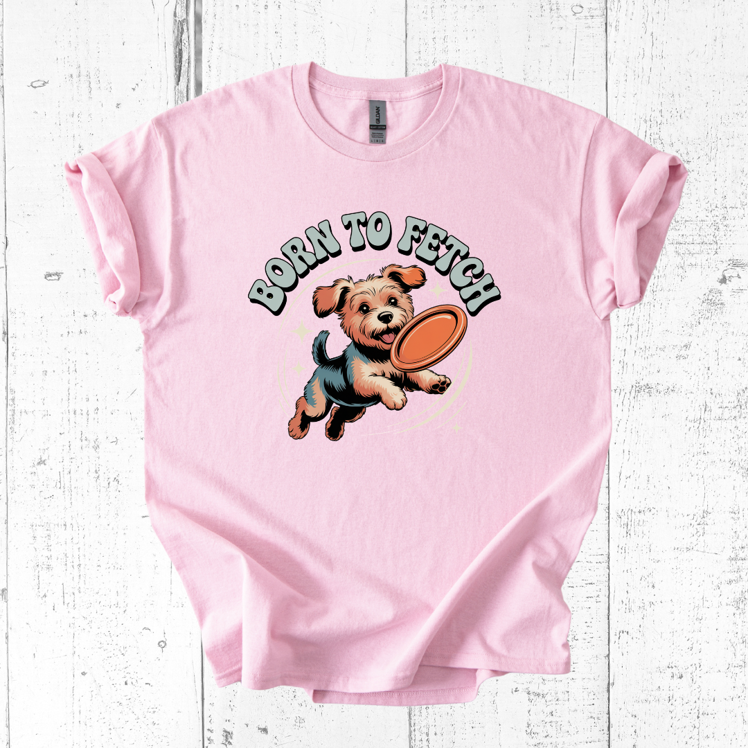 Pink t-shirt with a dog graphic and 'Born to Fetch' text on a white wooden surface