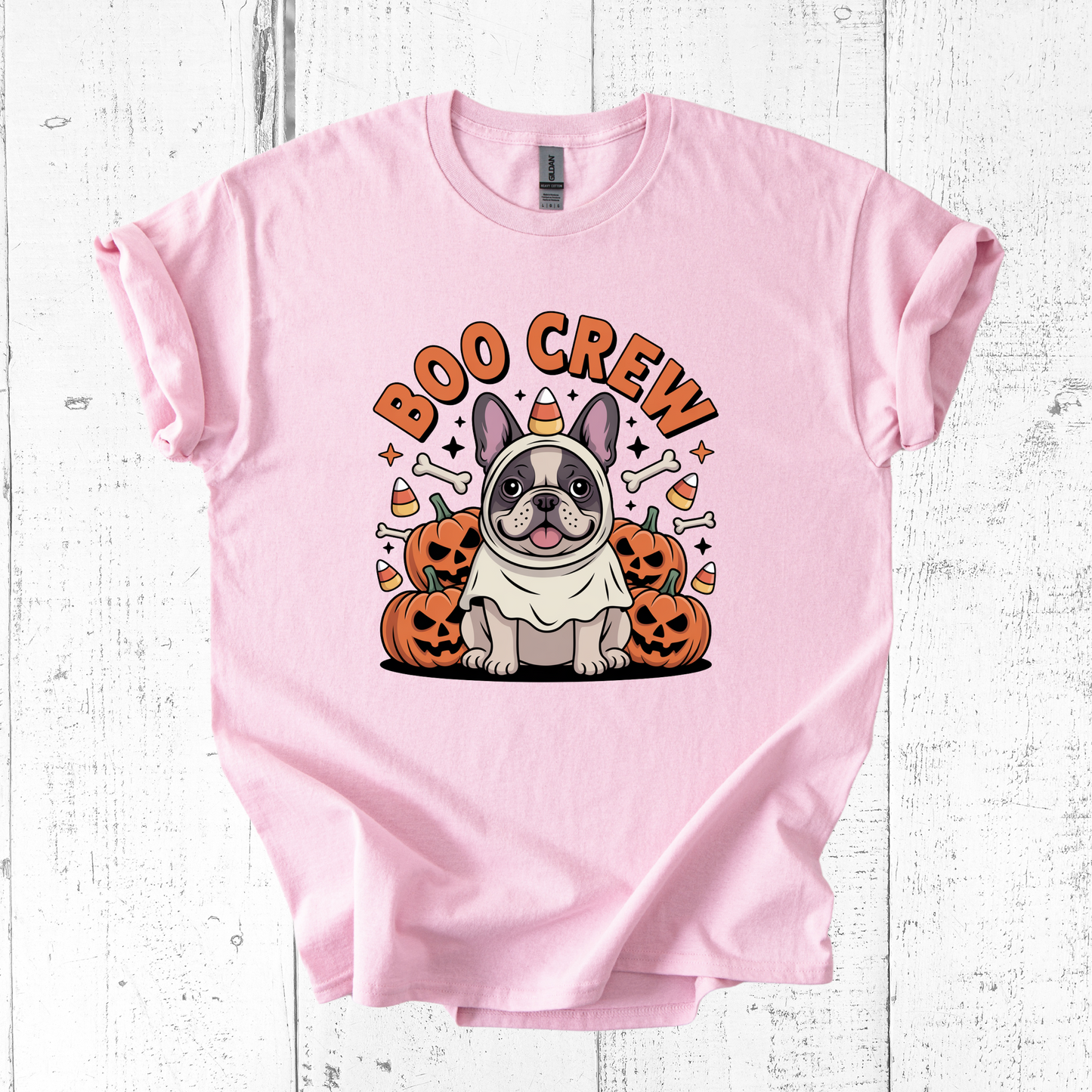 Pink t-shirt with a Halloween-themed design featuring a dog and pumpkins on a white wooden background.