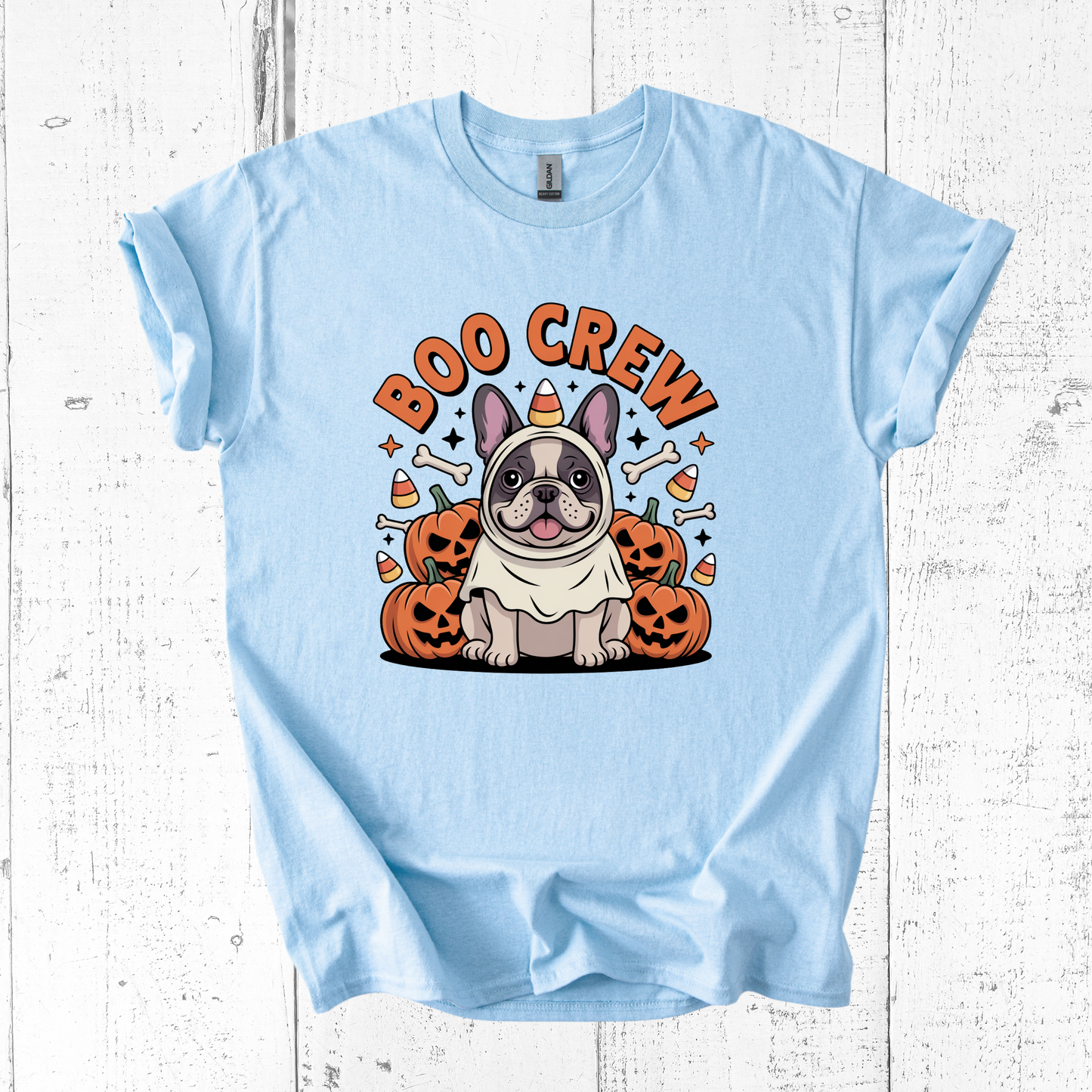 Light blue t-shirt with a Halloween-themed design featuring a dog and pumpkins on a white wooden background.