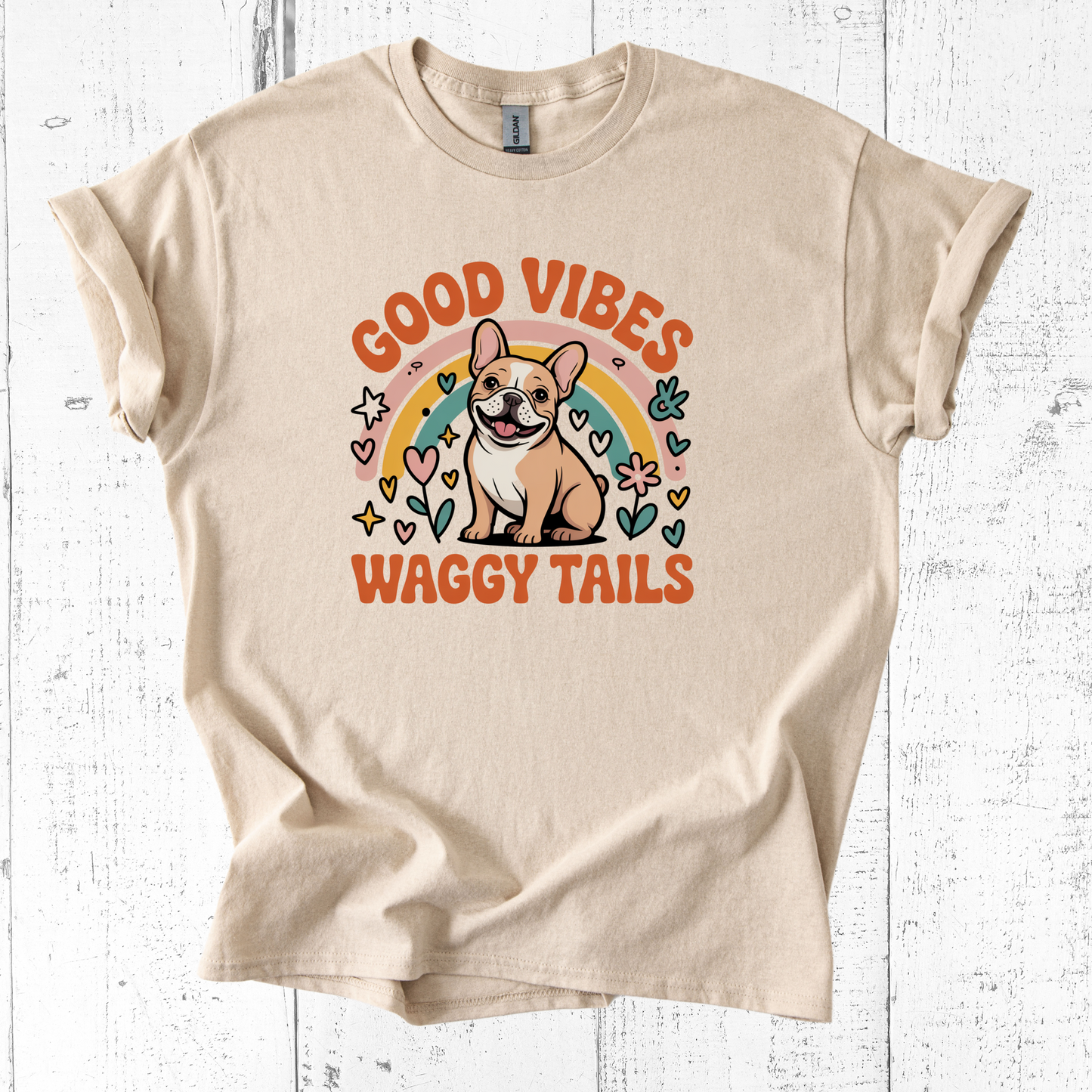 Beige t-shirt with a dog graphic and 'Good Vibes Waggy Tails' text on a white wooden background