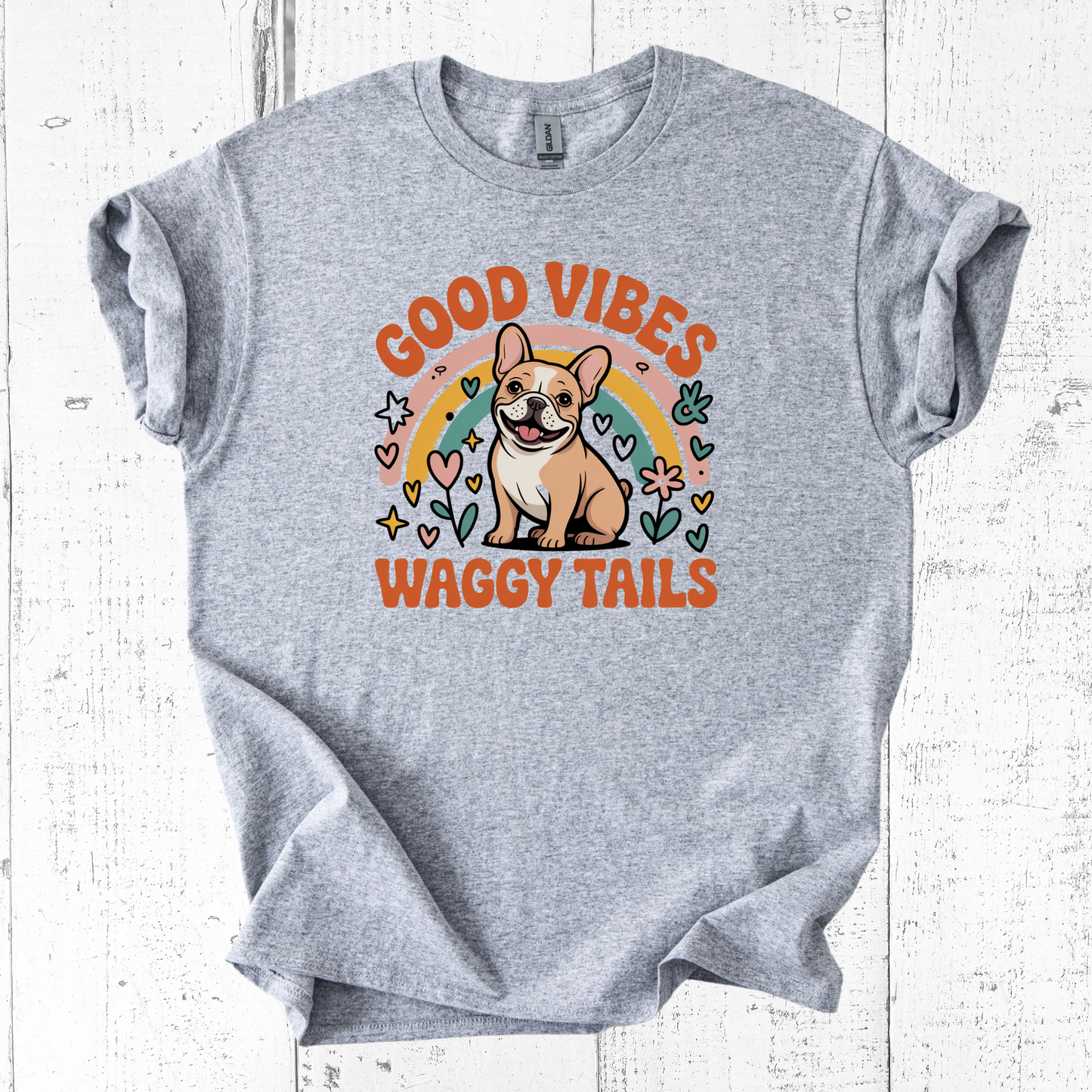 Gray t-shirt with a dog graphic and 'Good Vibes Waggy Tails' text on a white wooden background