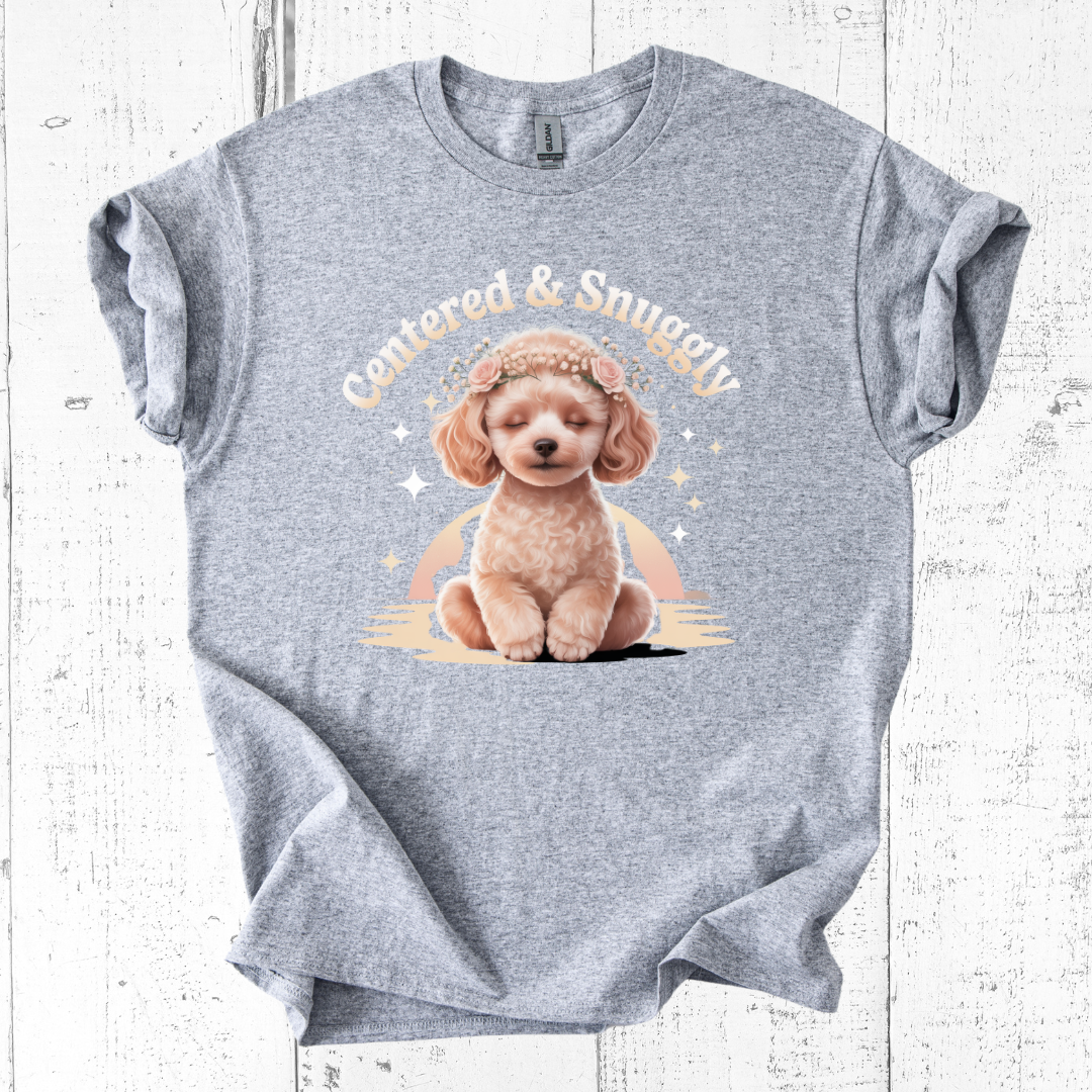 Gray t-shirt with a graphic of a dog and text 'Cuddled & Snuggly' on a wooden surface.