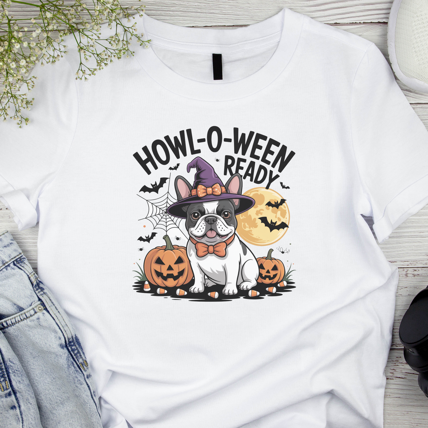 White t-shirt with Halloween-themed design featuring a dog in a witch hat and pumpkins on a wooden surface.