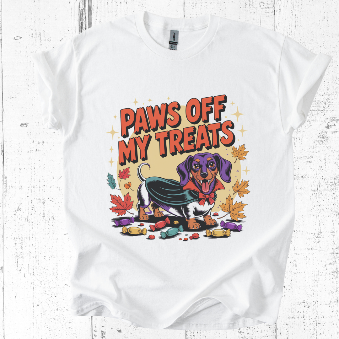 White t-shirt with a graphic of a dog and 'Paws Off My Treats' text on a wooden surface