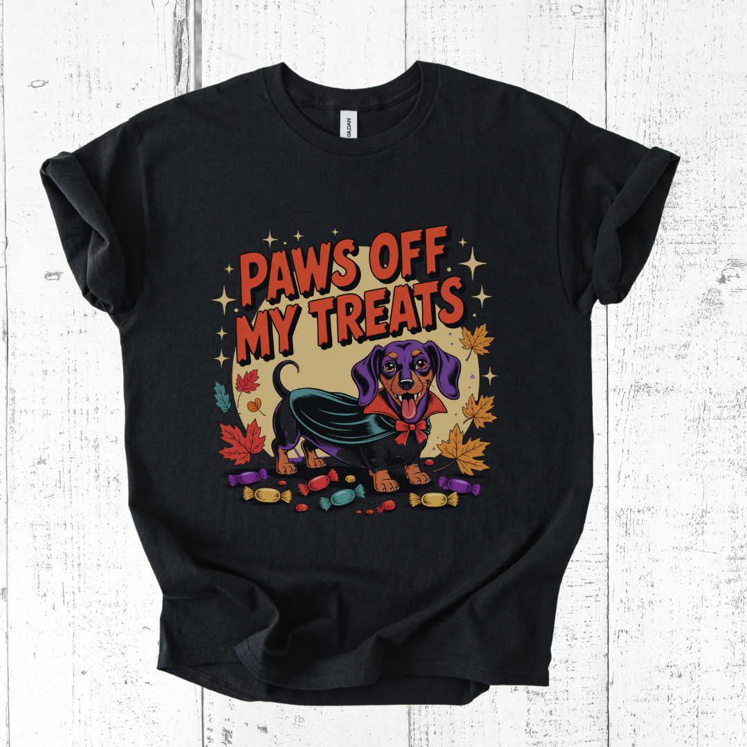 Black t-shirt with a Halloween-themed graphic of a dog and text 'Paws Off My Treats' on a wooden surface.