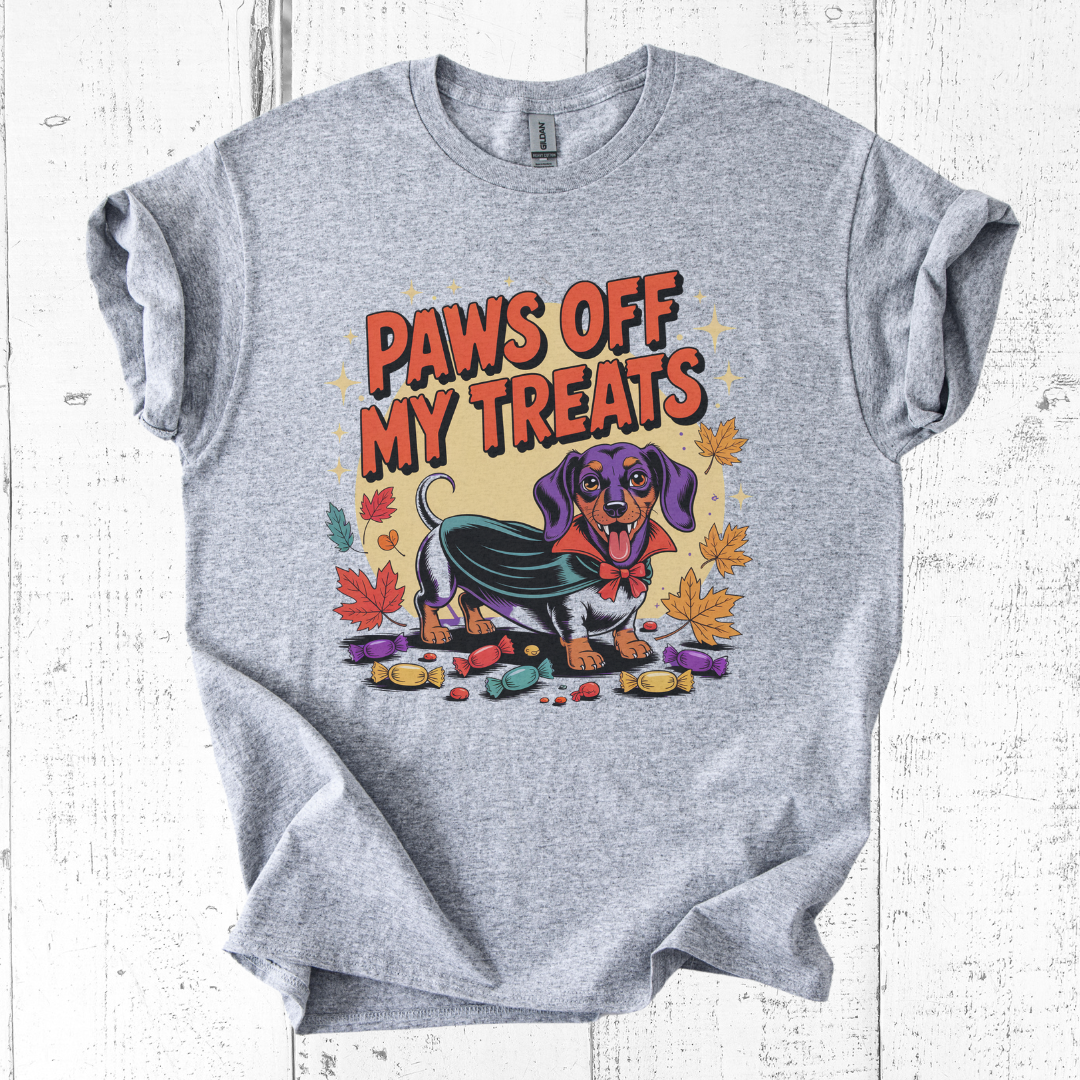 Gray t-shirt with a colorful graphic of a dachshund and text 'Paws Off My Treats' on a white wooden background.