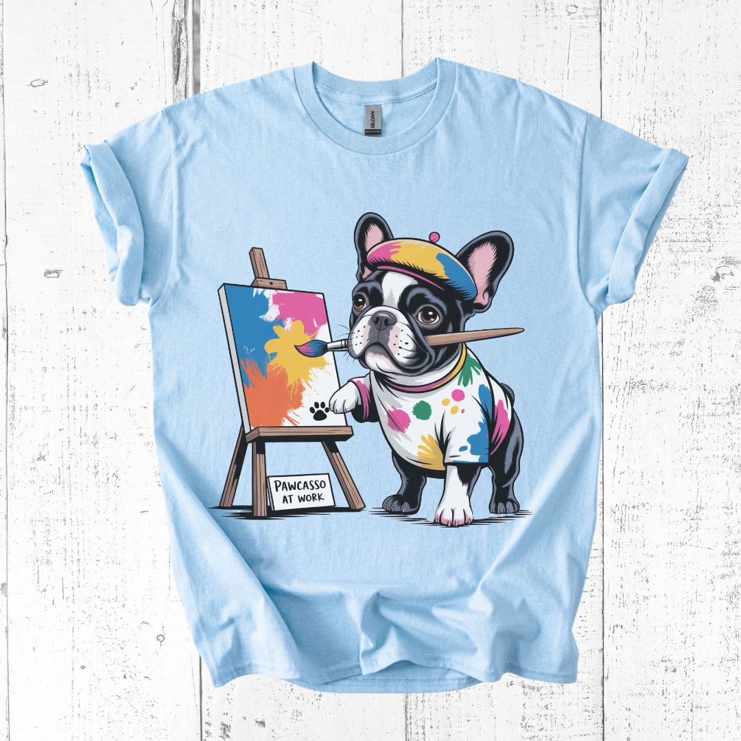 Light blue t-shirt with a cartoon dog painting design on a white wooden background
