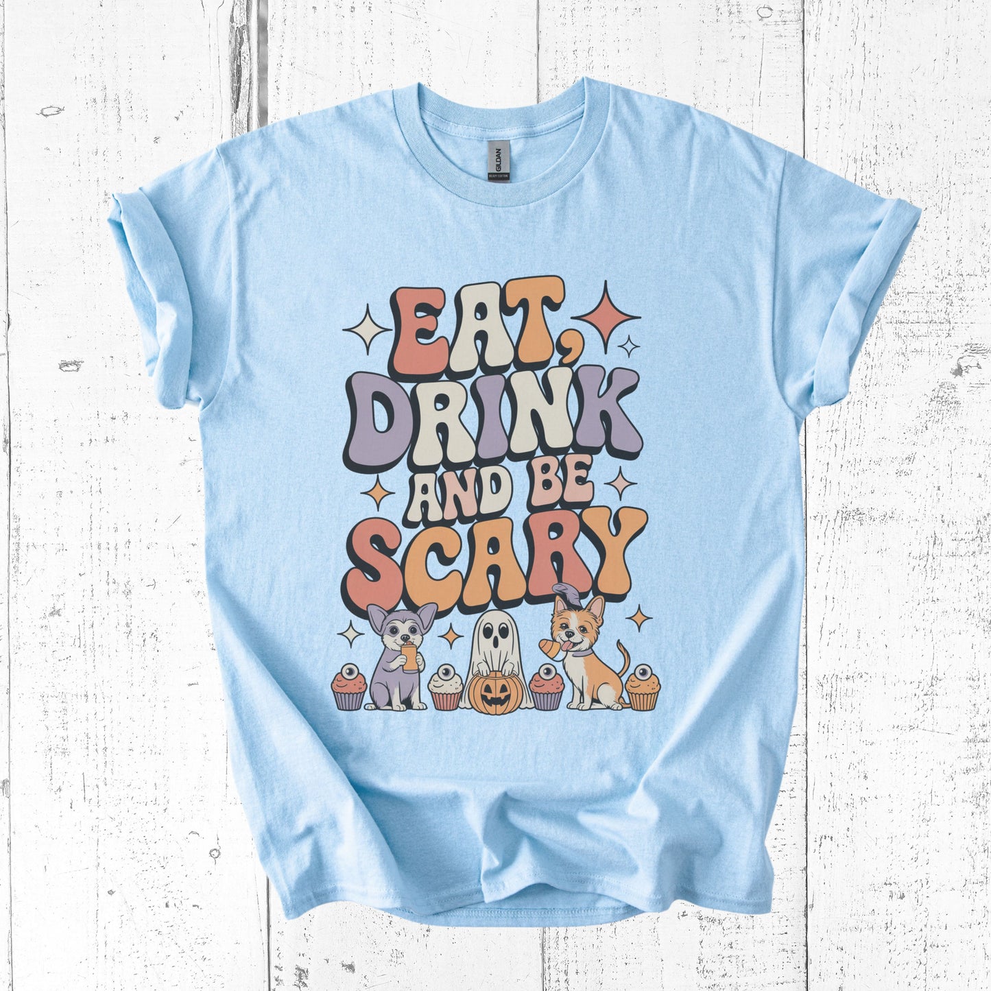 Light blue t-shirt with Halloween-themed design on a wooden surface