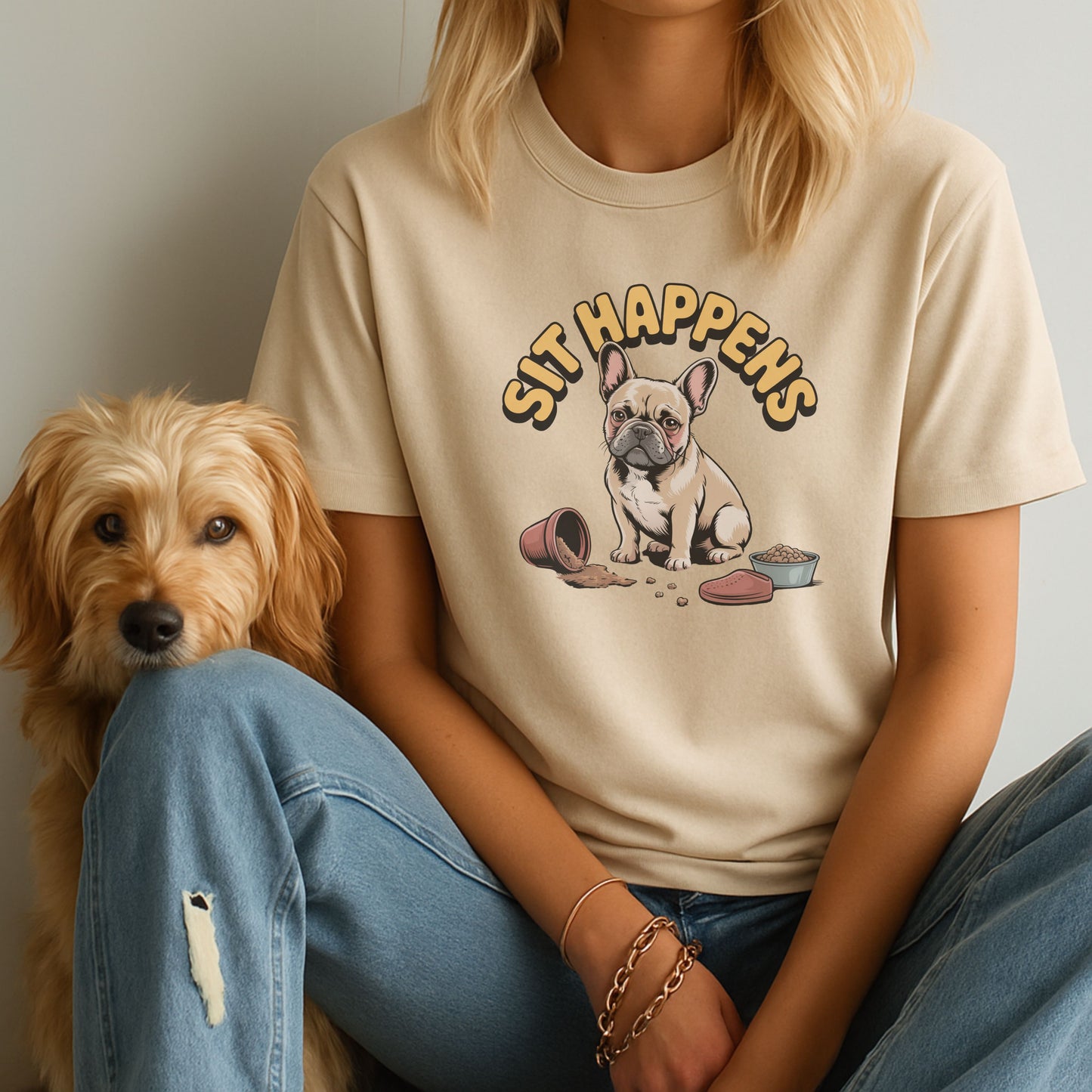 Person wearing a beige t-shirt with a dog graphic and 'SIT HAPPENS' text, sitting next to a dog.