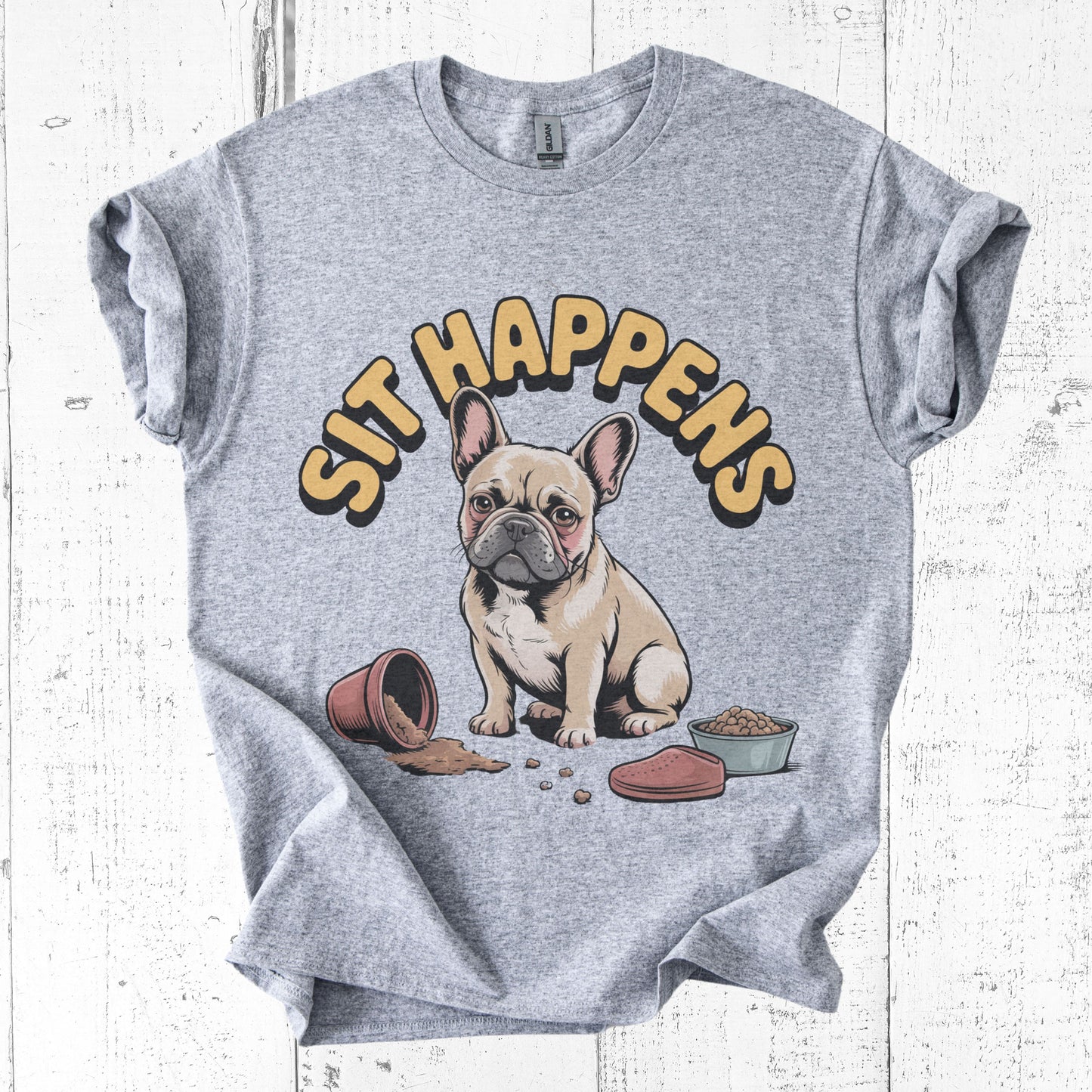 Gray t-shirt with a cartoon dog and 'Sit Happens' text on a white wooden background