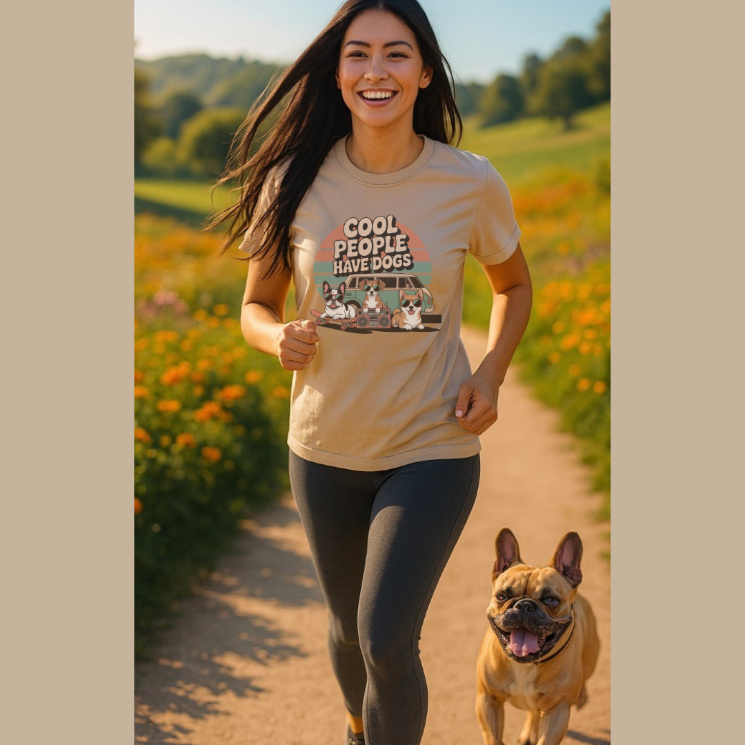 Woman running with a dog on a path in a field, wearing a t-shirt with a graphic design.