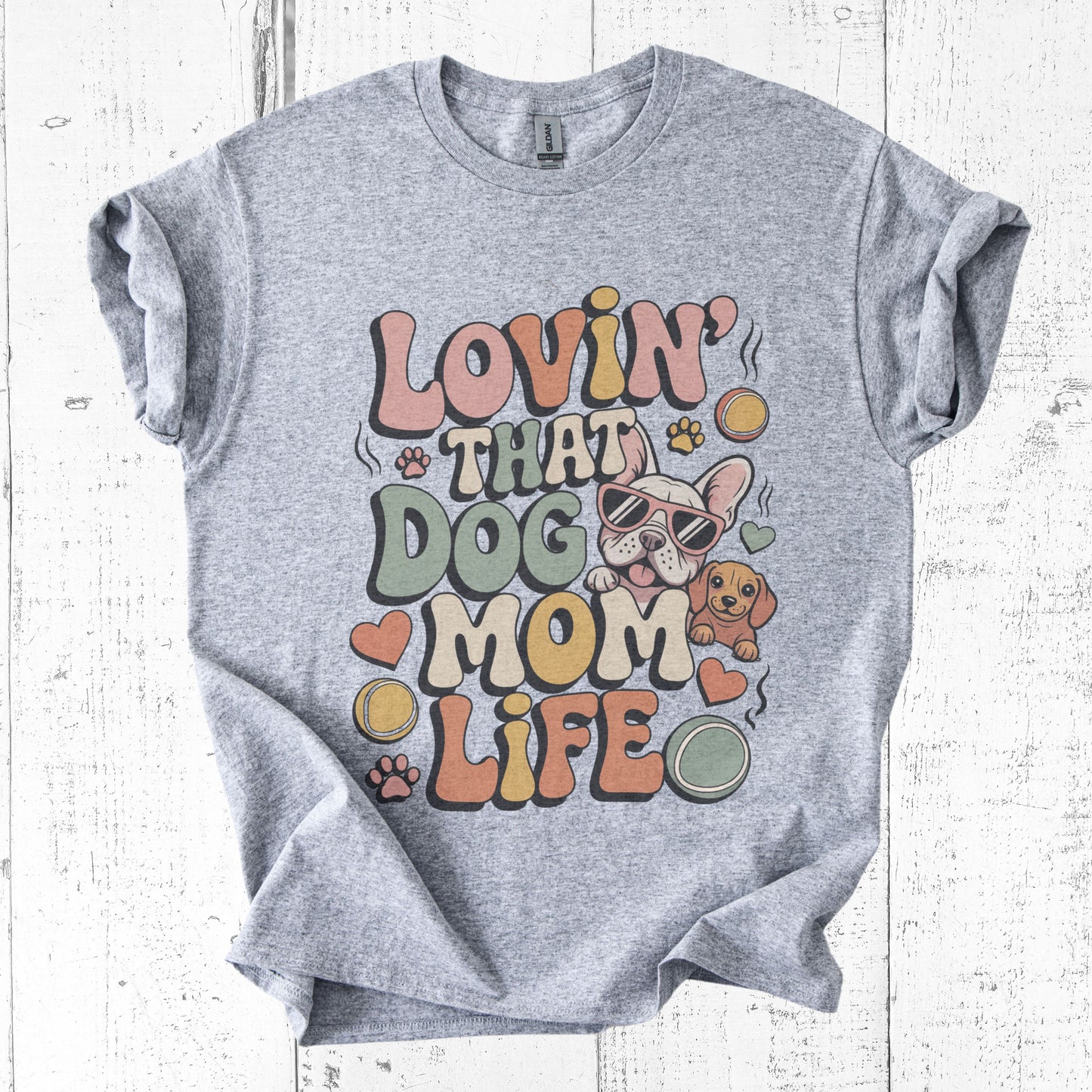 Gray t-shirt with 'Lovin' That Dog Mom Life' graphic design on a white wooden background