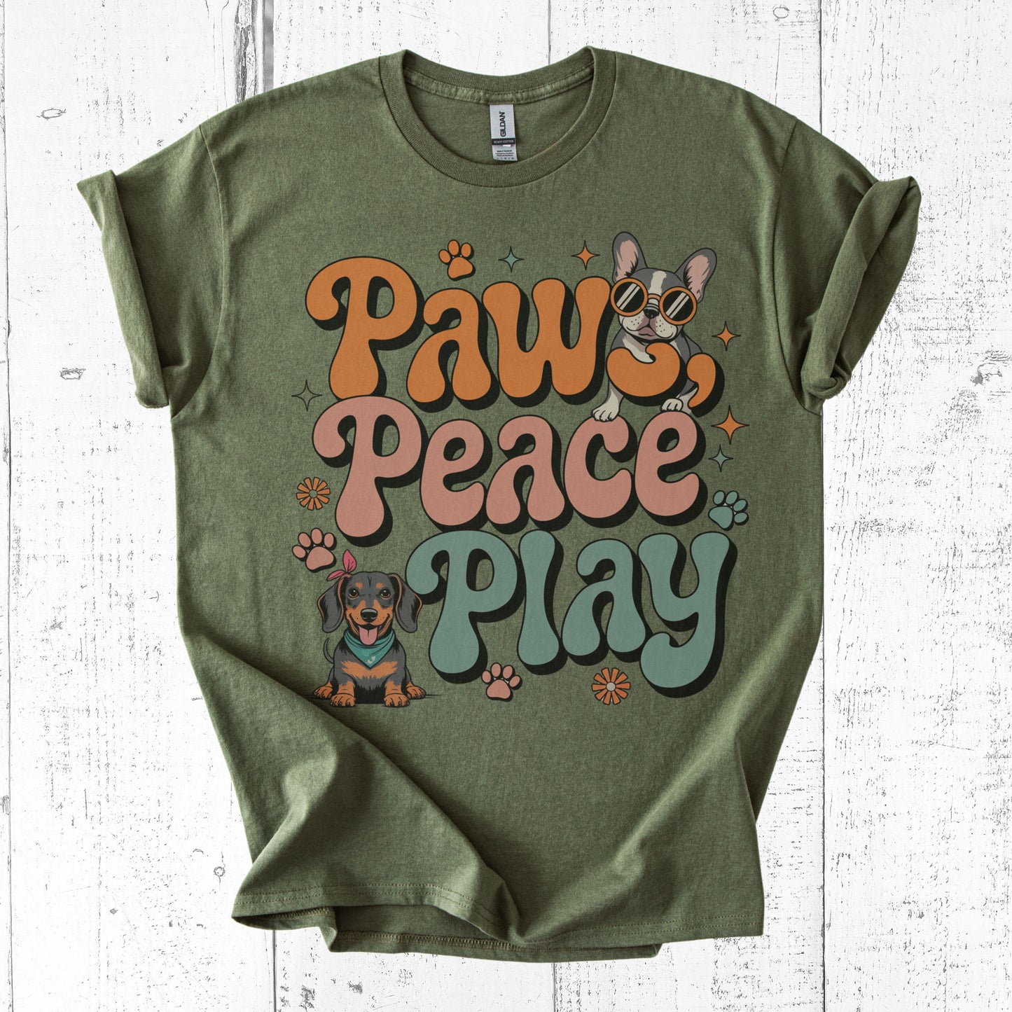 Green t-shirt with 'Paw Peace Play' text and dog graphics on a white wooden background