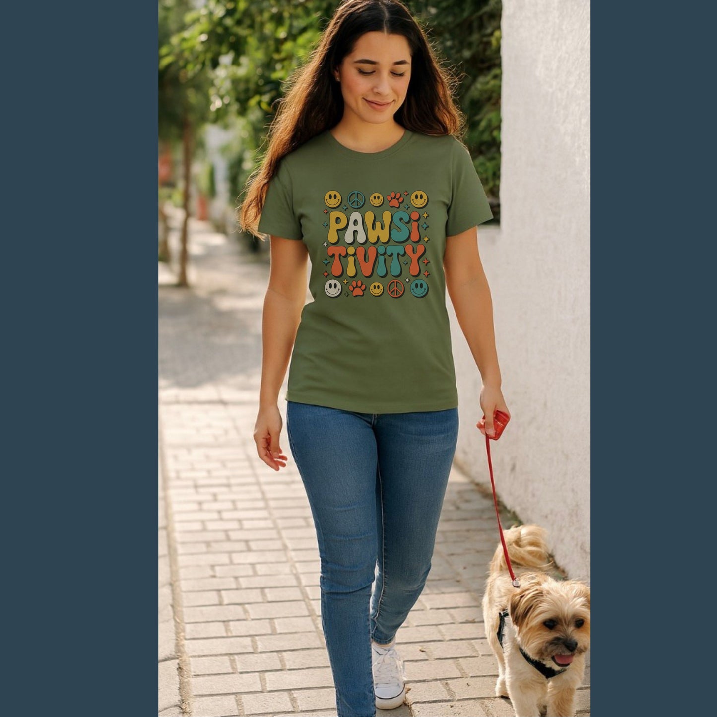 Woman walking a dog on a leash, wearing a green t-shirt with colorful text design.
