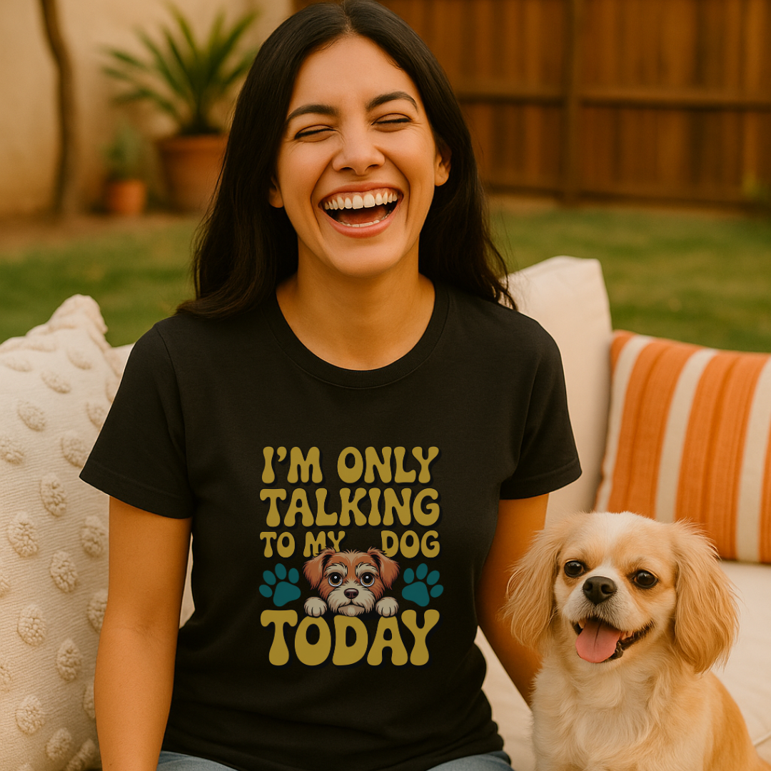 Woman wearing a black t-shirt with a dog graphic and text, sitting on a couch with a dog next to her.