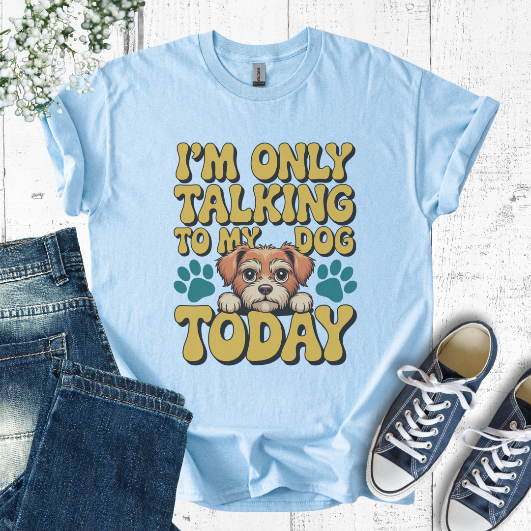 Light blue t-shirt with a dog graphic and text, paired with jeans and sneakers on a wooden surface.