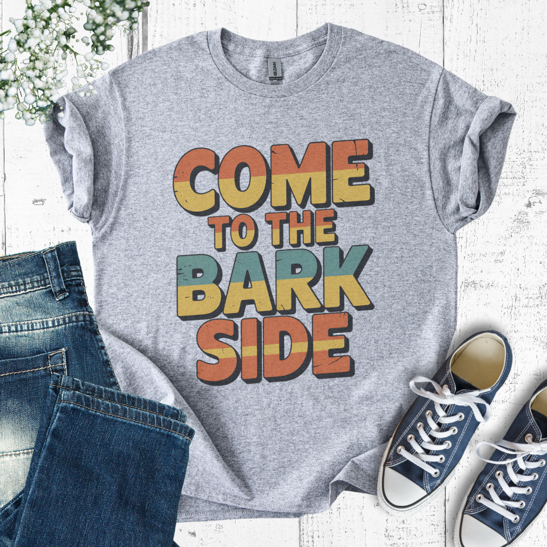 Gray t-shirt with 'Come to the Bark Side' text, paired with jeans and sneakers on a light wooden surface.