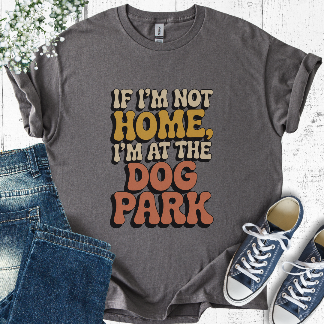 Gray t-shirt with 'If I'm not home, I'm at the dog park' text, paired with jeans and sneakers on a light wooden surface.