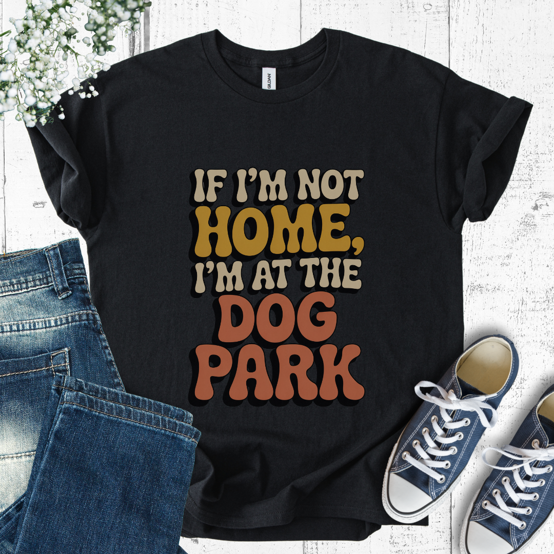 Black t-shirt with colorful text 'If I'm not home, I'm at the dog park' on a white background with jeans and sneakers.