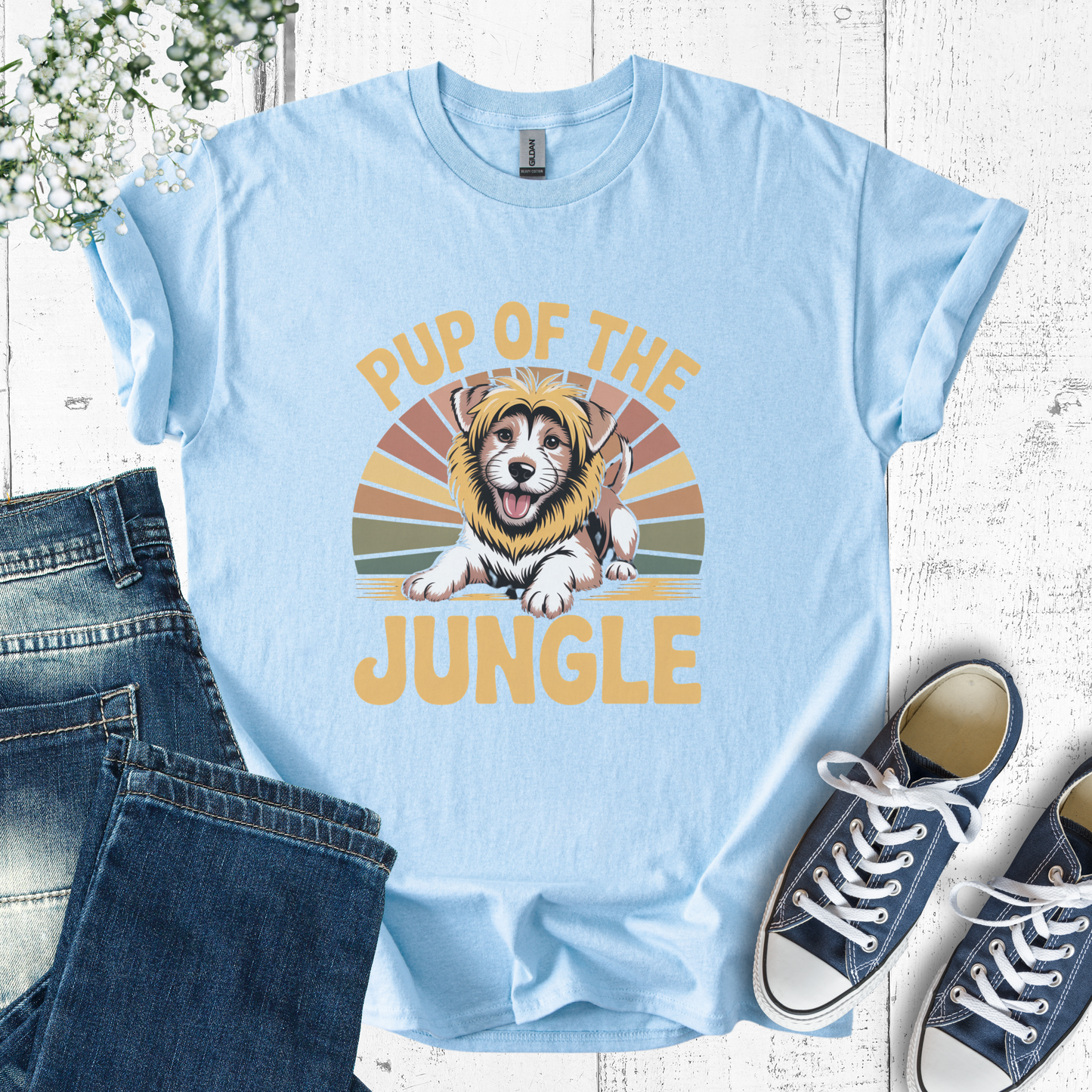 Light blue t-shirt with a dog graphic and 'Pup of the Jungle' text, paired with jeans and sneakers on a wooden surface.