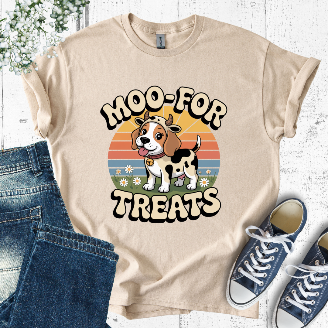Beige t-shirt with a cow and dog graphic and 'Moo-For Treats' text, paired with jeans and sneakers on a white wooden surface.