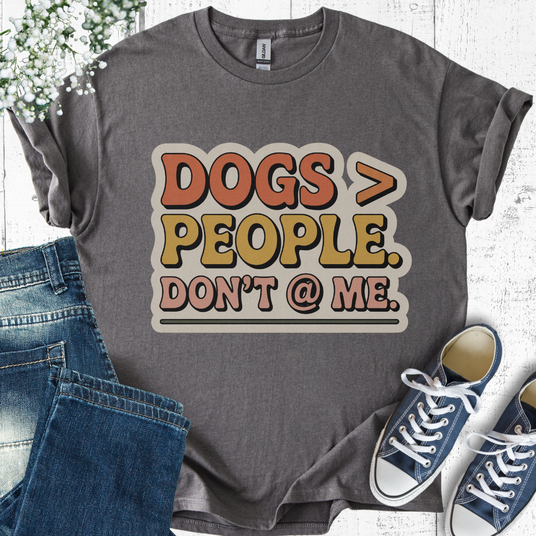 Gray t-shirt with 'DOGS > PEOPLE. DON'T @ ME.' text, paired with jeans and sneakers on a light wooden surface.