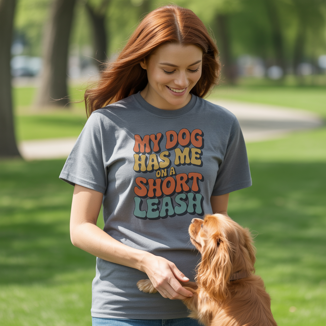 Woman wearing a t-shirt with a dog-themed message, standing with a dog in a park.