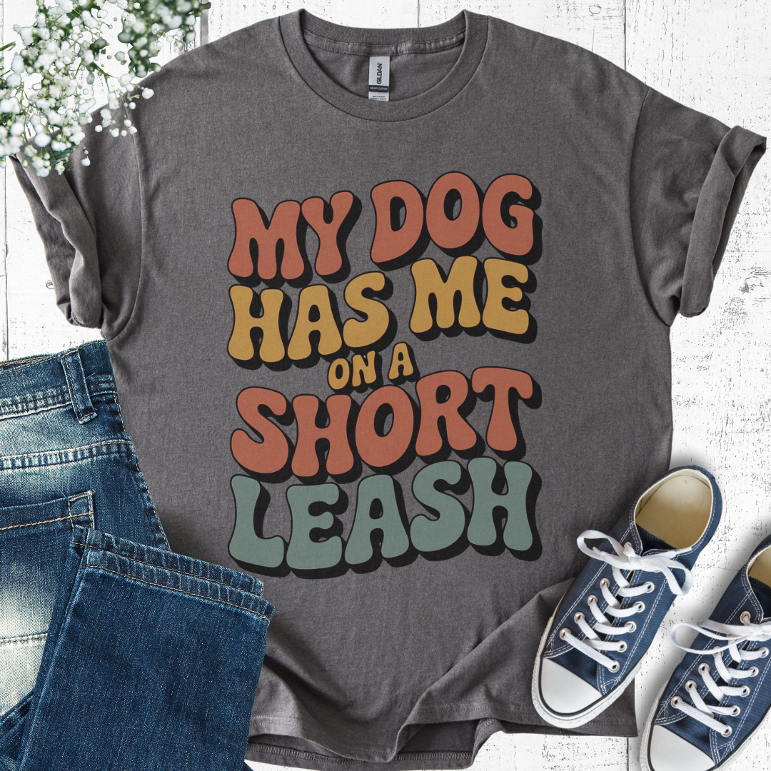 Gray t-shirt with colorful text 'My dog has me on a short leash' displayed with jeans and sneakers.