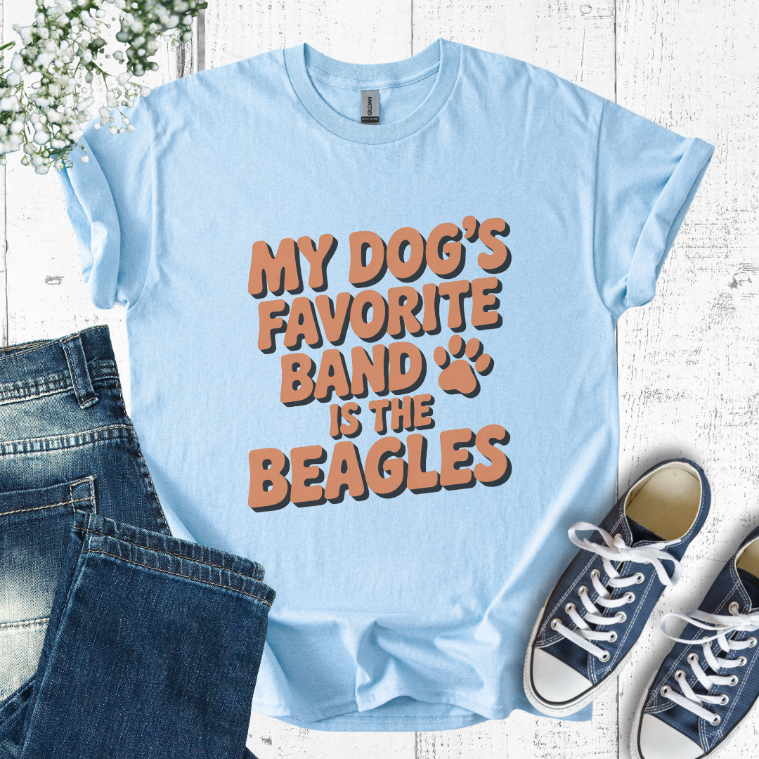 Light blue t-shirt with 'My dog's favorite band is the beagles' text, paired with jeans and sneakers on a wooden surface.