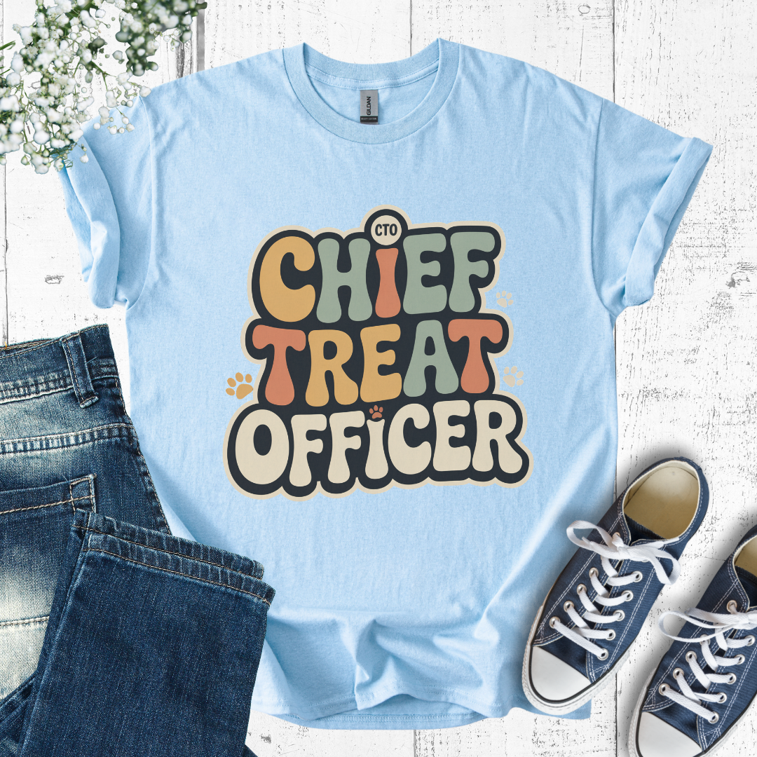 Light blue t-shirt with 'Chief Treat Officer' text, paired with jeans and sneakers on a wooden surface.