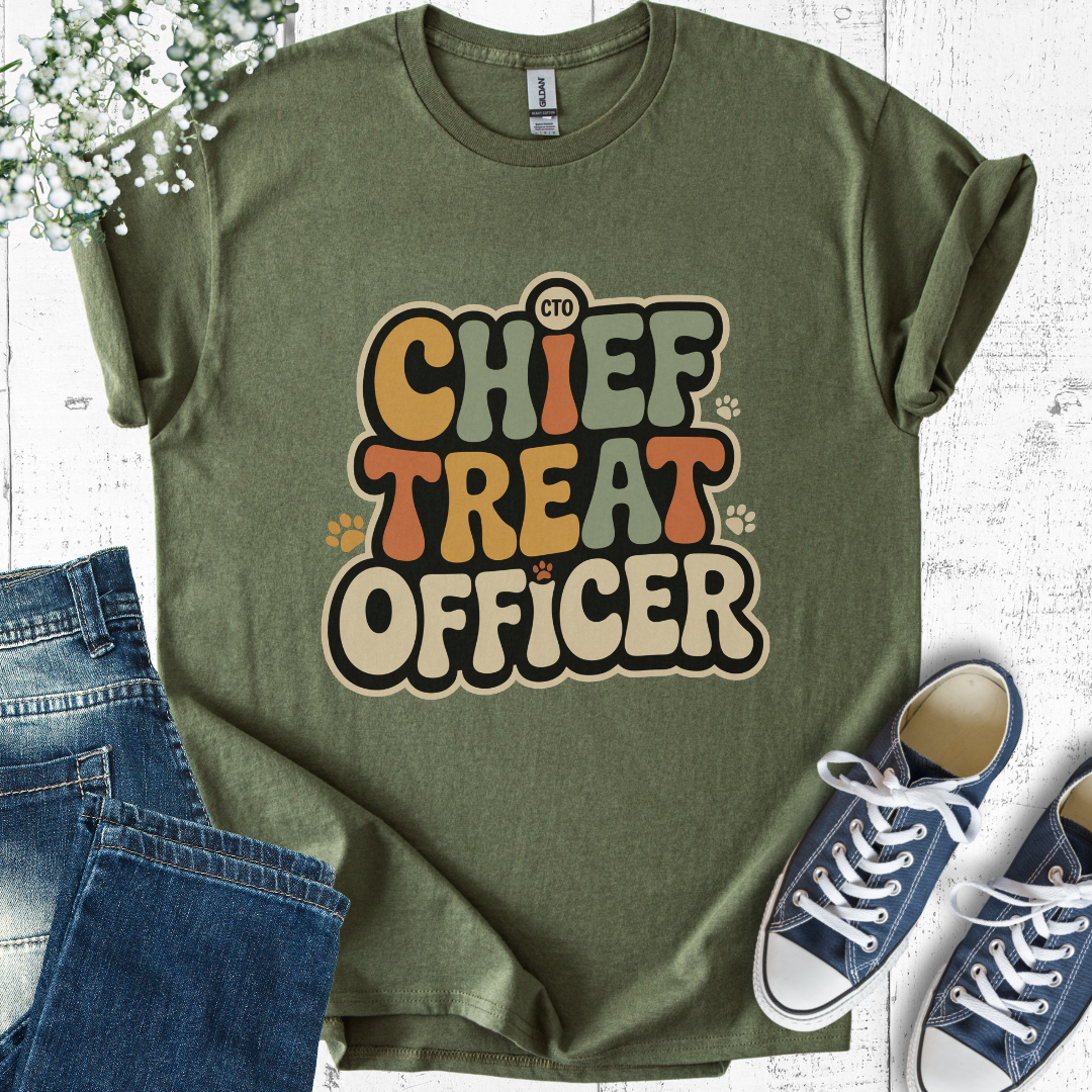 Green t-shirt with 'Chief Treat Officer' text, jeans, and sneakers on a light wooden surface.