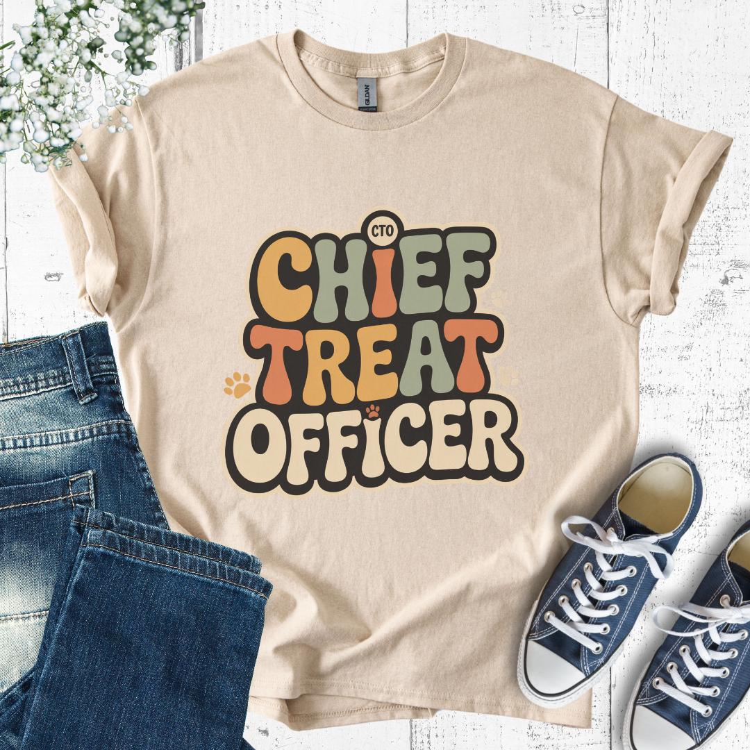 Beige t-shirt with 'Chief Treat Officer' text, paired with jeans and sneakers on a light wooden surface.