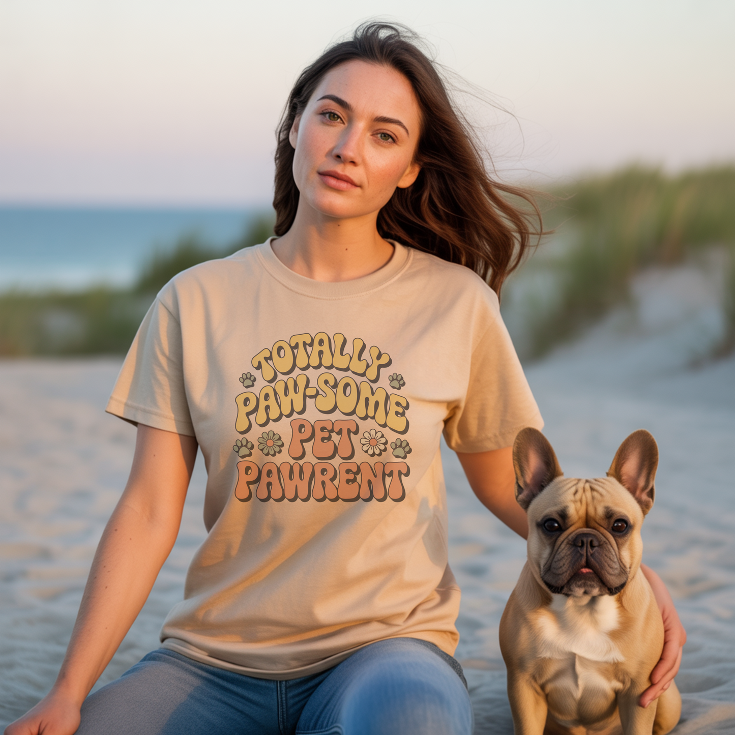 Woman wearing a t-shirt with 'Totally Paw-some Pet Parent' on a beach with a dog.