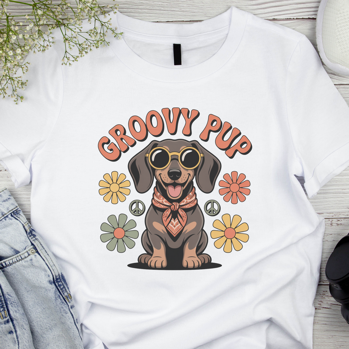 White t-shirt with a dachshund graphic and 'Groovy Pup' text on a wooden surface.