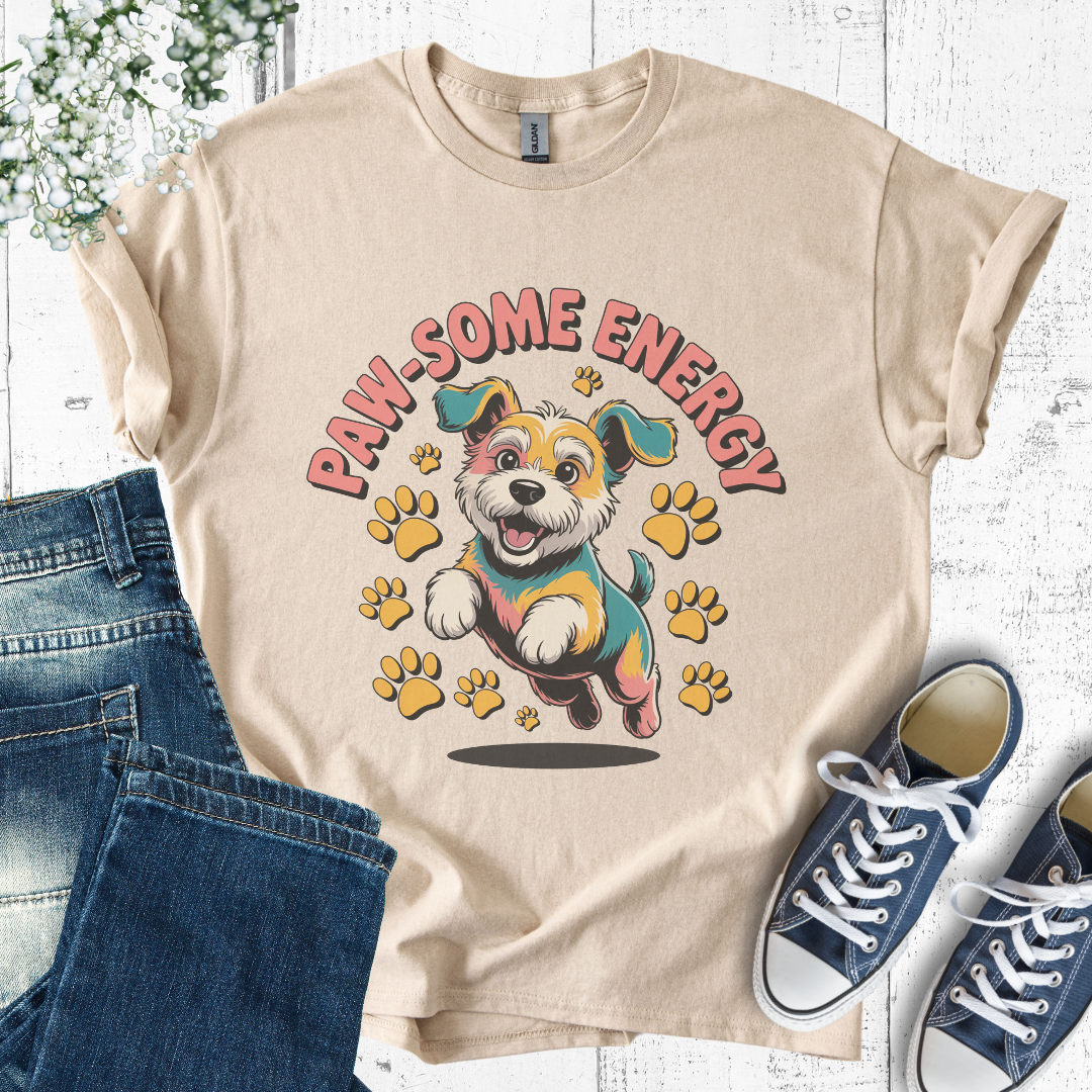 Beige t-shirt with a dog graphic and 'PAW-SOME ENERGY' text, paired with jeans and sneakers on a light wooden surface.